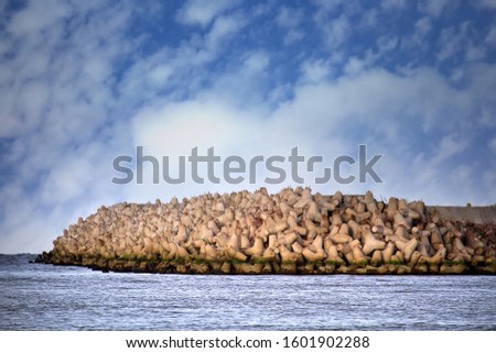 The seawall around the sea port facilities is made of concrete tetrapods (traveling-wave protection), rubble-mound breakwater Royalty-Free Stock Photo #1601902288