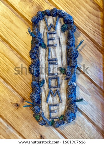 Just a photo of a hand made welcome sign hanging on a cedar wall.