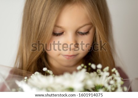 Close up portrait of beautiful teen romantic girl holding bouquet of white spring flowers at her face smelling it aroma with closed eyes in white background. First flowers for mom