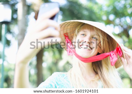 Blonde female model posing for her selfie on her phone. Woman taking a selfie on her phone on vacation. Smiling tourist. 