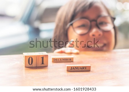 Girl happy and smile with flipping a cube letters, changing the word the change from January to December,New year concept.