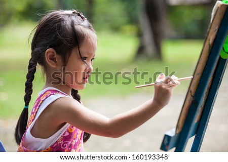 Little girl painting color on easel Royalty-Free Stock Photo #160193348