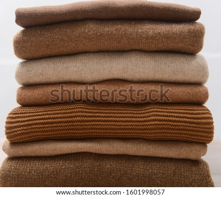 Pile of knitted woolen sweaters autumn colors on wooden


