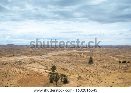 Aerial view of Tunisian countryside landscape and empty road. Many plastic trash laying on ground. Horizontal color photography.