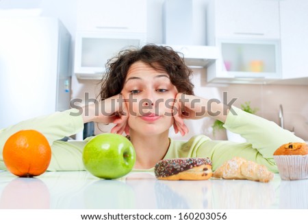 Diet. Dieting concept. Healthy Food. Beautiful Young Woman choosing between Fruits and Sweets. Weight Loss  Royalty-Free Stock Photo #160203056
