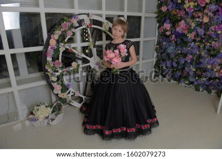 cute girl princess in a black dress with a becket of flowers in her hands