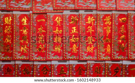 Closeup chinese new year greetings printed with gold color on red paper hanging in front of a store, the chinese words mean happy new year, wealth, prosperity and wishes come true