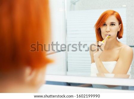 Pretty girl brushes her teeth in a bright bathroom