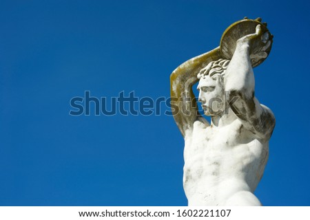 Ancient Greek statue of discus thrower displaying athletic prowess in white marble under bright blue sky