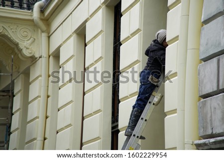 Female house painter. Photo of a female painting a wall with a roller and yellow paint