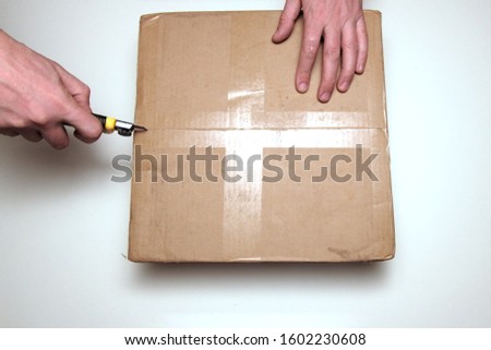 Men unpacking boxknife knife. View from above. The concept of delivery and verification of online purchases or opening a gift.