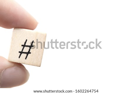 Hand holding a wooden cube with a hashtag a symbol near white background, social media concept space for text close-up