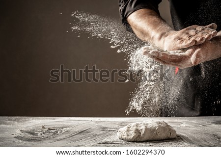 Photo of flour and men hands with flour splash. Cooking bread. Kneading the Dough. Royalty-Free Stock Photo #1602294370