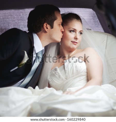 Classic wedding picture of a young couple in limo.