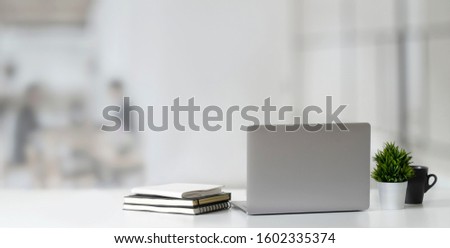 Cropped shot of open laptop computer on wooden table and copy space with blurred office background