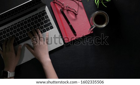 Close-up view of young businesswoman typing on laptop computer while working on his project in dark luxury workplace 