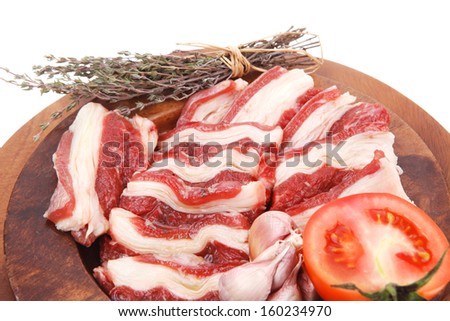 natural raw beef asado ribs with thyme and tomatoes on wooden board isolated over white background