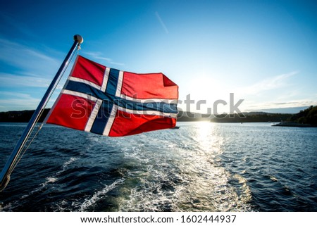 Norwegian flag on a ship or boat with the Oslo fjord in Norway in the background, sightseeing ferry Royalty-Free Stock Photo #1602444937