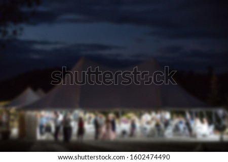Abstract blur of outdoor wedding reception under a tent.