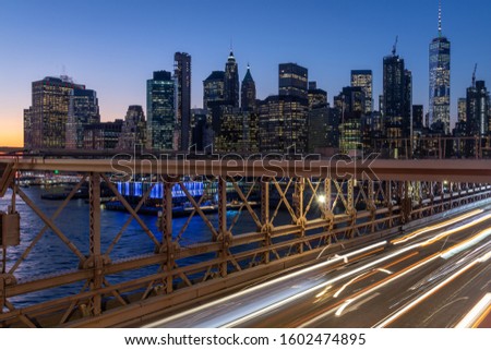 New York skyline from Brooklyn Bridge at night with light trails from moving cars