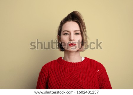 Young woman wearing warm sweater and posing on yellow wall. High quality photo