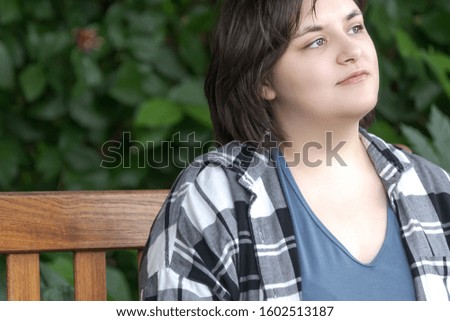 confident young woman with short hair in her 20's sitting outside on bench