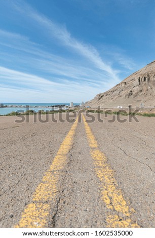 Double yellow line on abandoned road with hill in the background