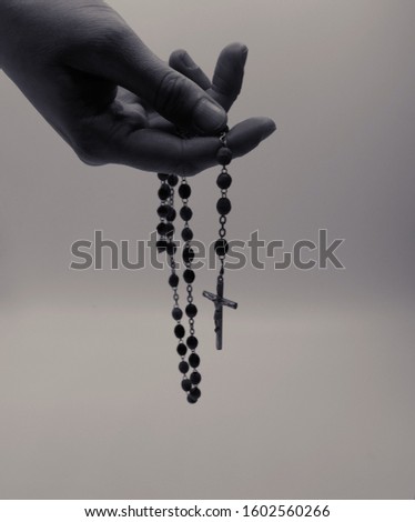 hand holding rosary in black and white