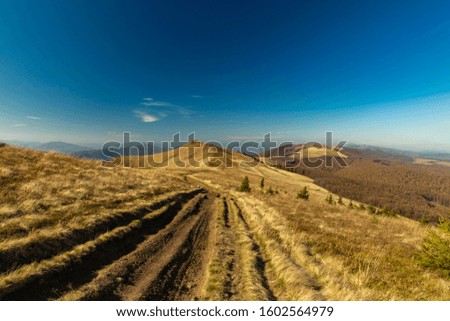 dirt trail along mountain range highland scenic landscape photography in autumn time season clear weather day without people, blue sky background empty copy space for text 