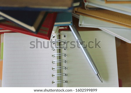 A close up of a notebook on the library desk A pile of books in the background selective focus and shallow depth of field