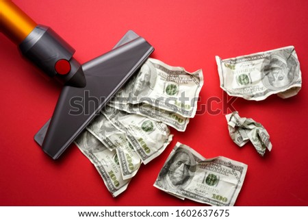 vacuum cleaner nozzle sucking money dollar bill on red background
