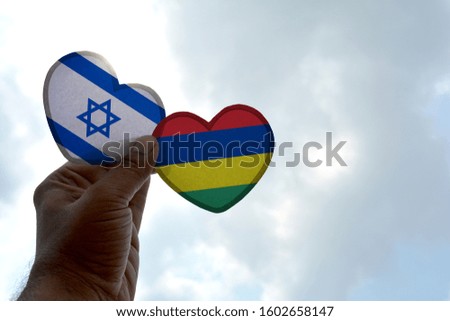 Hand holds a heart Shape Israel and Mauritius flag, love between two countries