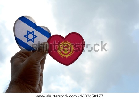 Hand holds a heart Shape Israel and Kyrgyzstan flag, love between two countries