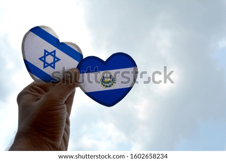Hand holds a heart Shape Israel and El Salvador flag, love between two countries