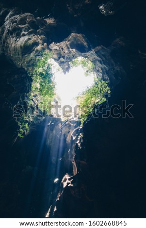 Sun rays come through the heart shape of hole cave