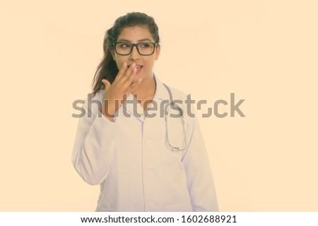 Thoughtful young happy Persian woman doctor smiling while looking shocked isolated against white background