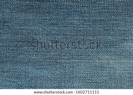 Heavy used blue jean denim top view close up shot to the detail of fabric. textile material and cotton patter tough and durable garment style. For background or wallpaper with copy space for text.