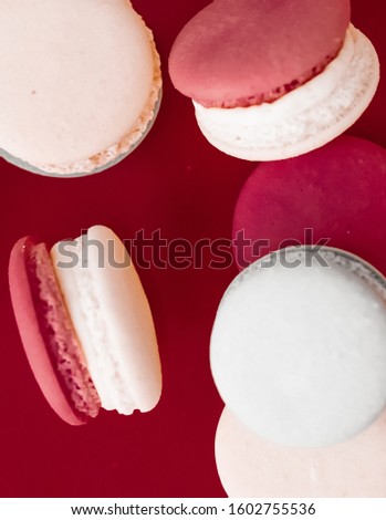 Pastry, bakery and branding concept - French macaroons on wine red background, parisian chic cafe dessert, sweet food and cake macaron for luxury confectionery brand, holiday backdrop design