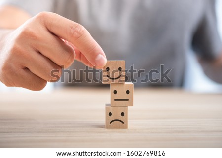 Hand of a businessman chooses a smiley face on wood block cube, The best excellent business services rating customer experience, Satisfaction survey concept