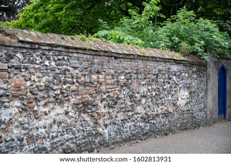 Crumbling wall with exposed bricks and stones in a quiet city street