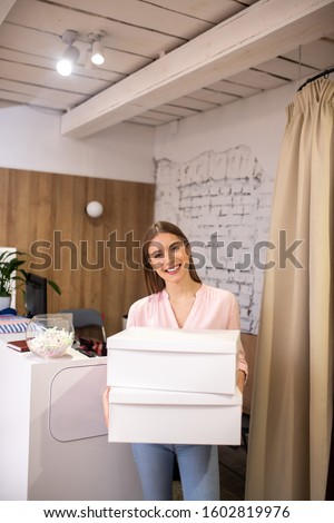 Making purchases. A smiling shop administrator holding boxes with orders