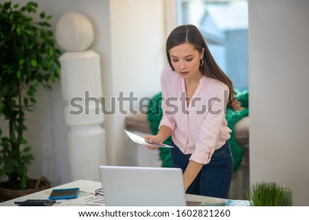 Busy with work. Nice serious woman looking at the laptop screen while