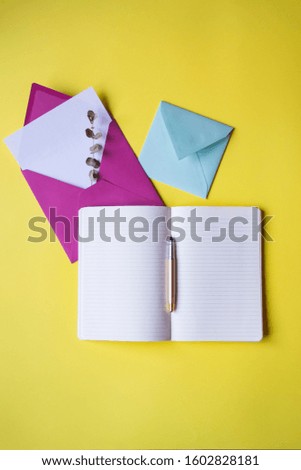 Opened notebook and colorful envelopes with note blank on the yellow background. Background with copy space.
