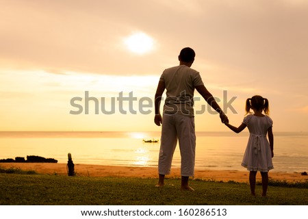 father and daughter standing at the beach in the dawn time