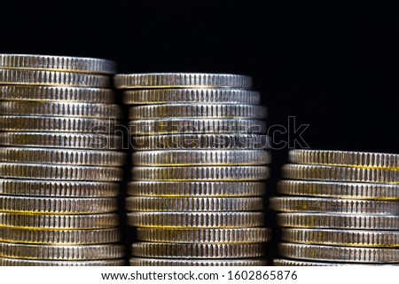 a large number of pile of beautiful old coins with ribbed side, lie together, close-up photo of real metal money illuminated by colored light