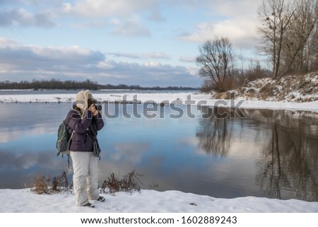 Woman making the pictures on the Bank of the Vistula river during the winter. Poland. Natura 2000