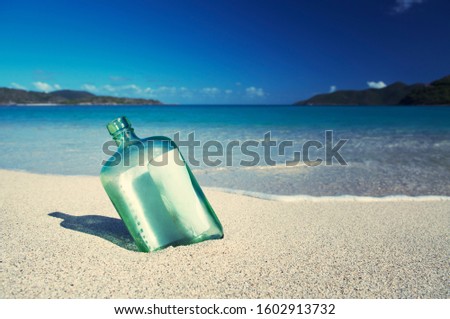 Message in a glass bottle washed up on the shore of a tropical desert island beach