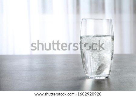 Glass with effervescent tablet on grey table indoors, space for text. Medical care