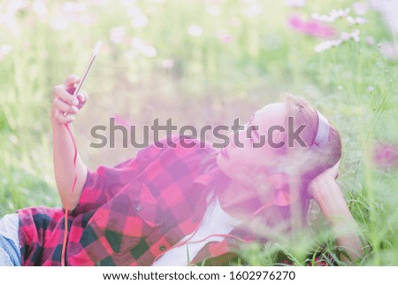 A young girl lying on the grass listening to music, relax on soft and blurred background