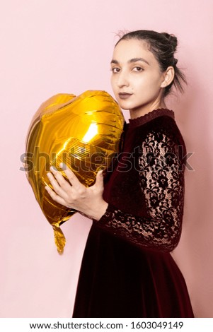 Attractive iranian woman hold golden heart shaped air balloon. Celebrating Valentines day. Beautiful Happy Young middle-eastern girl. Holiday party, Love day, anniversary, birthday celebration concept
